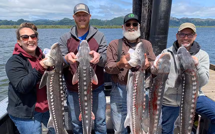 bx-sturgeon-fishing-1 four individuals holding sturgeon fish