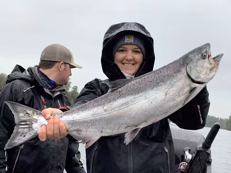 A woman displays her catch while enjoying best salmon fishing in oregon
