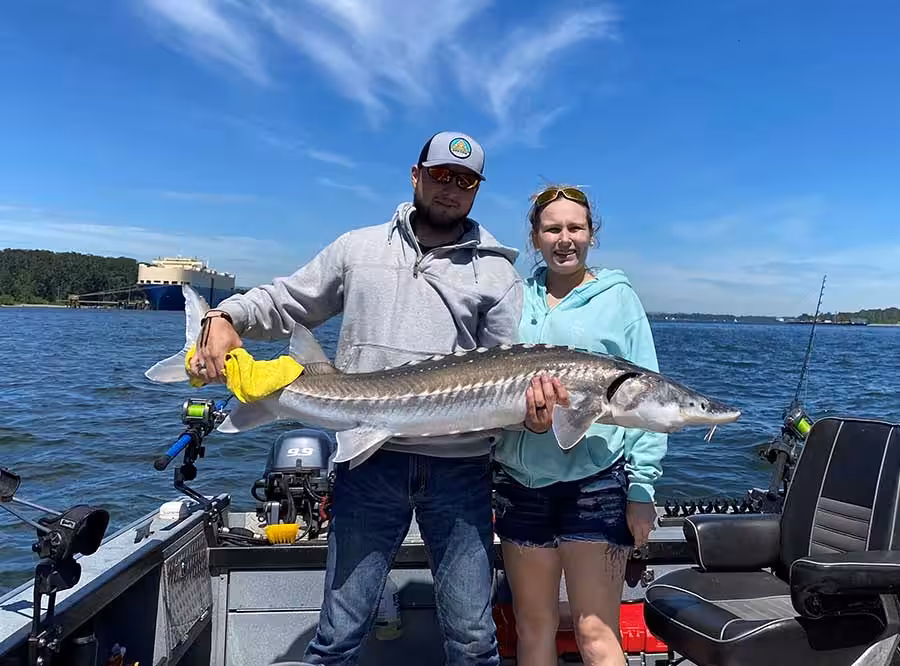 A couple holding sturgeon on a boat during a fishing in Portland Oregon.