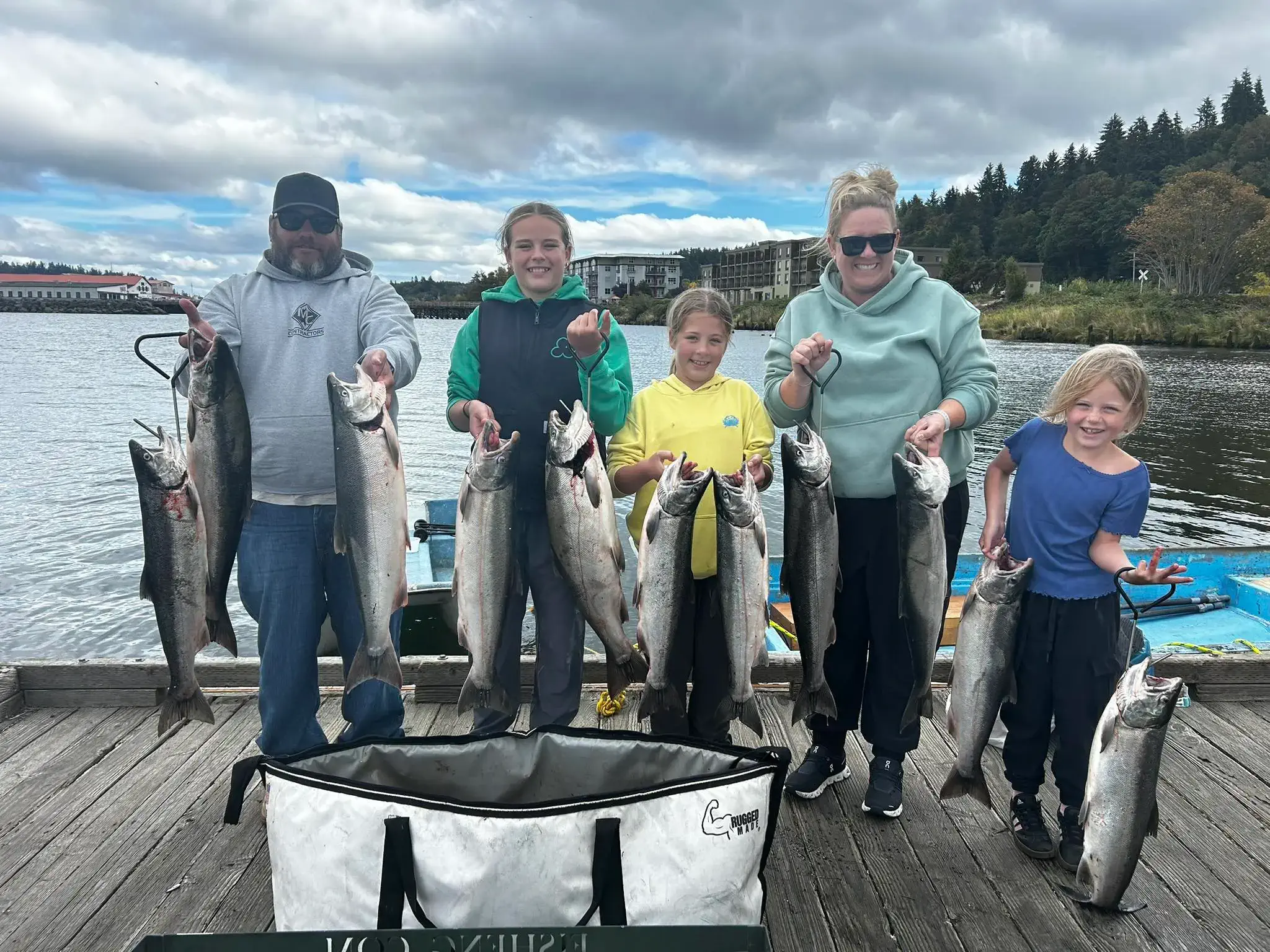 Five people on a dock holding large fish representing fishing activity for kids.