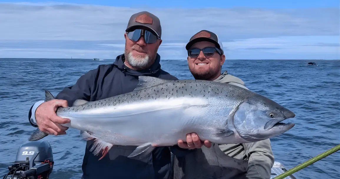 Oregon fishing guides holding a large fish on a boat