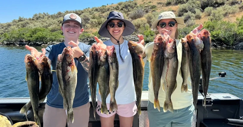 Three smiling people on a boat holding up several walleye to celebrate the joy of fishing.